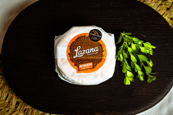 Queso Lazana afinado envuelto en papel sobre tabla de madera oscura