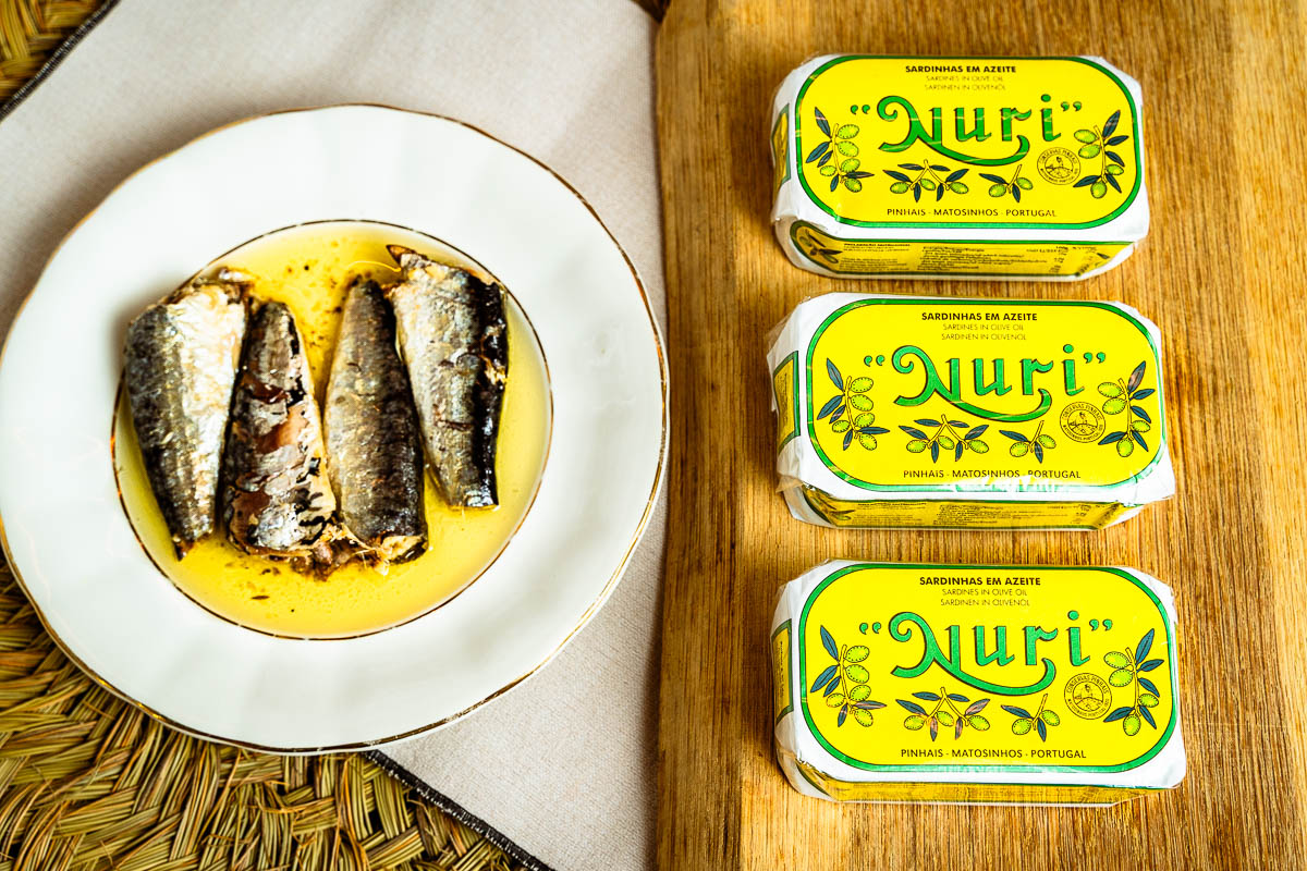 Lata de sardinas Nuri en aceite de oliva junto a un plato con sardinas